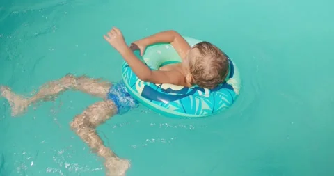 Happy little kid with inflatable ring playing in pool, laughing and splashing Stock Footage 260486269