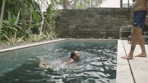 Happy lovers fool around in the pool in the luxurious villa in Bali Stock Footage