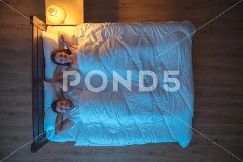 The happy lovers lay on the bed. evening night time. view from above Stock Photos