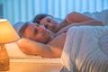 The happy lovers lie on the bed. Evening night time Photo