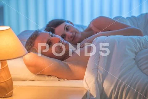 The happy lovers lie on the bed. Evening night time Stock Photos