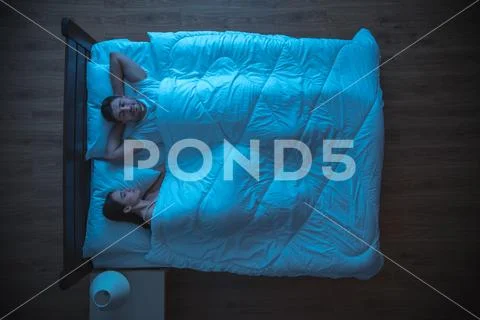 The happy lovers sleeping on the bed. evening night time. view from above Stock Photos
