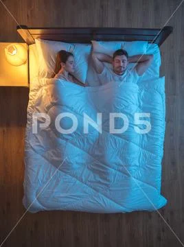 The happy lovers sleeping on the bed. evening night time. view from above Stock Photos