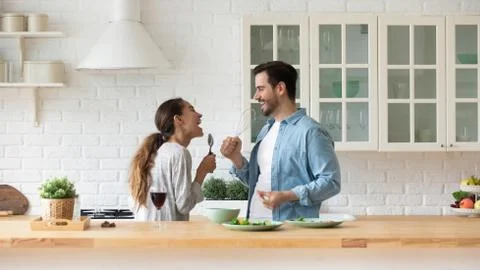 Happy loving couple singing, having fun with kitchenware in kitchen Stock Photos