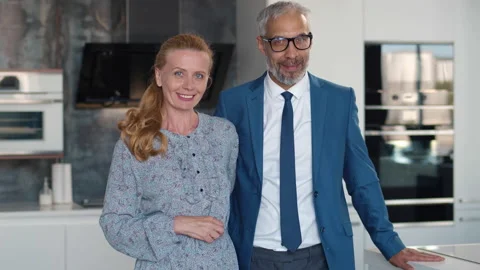 Happy loving mature couple embracing looking at camera standing in kitchen Stock Footage 234065563