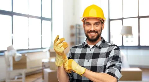 Happy male builder in helmet and gloves at home Stock Photos