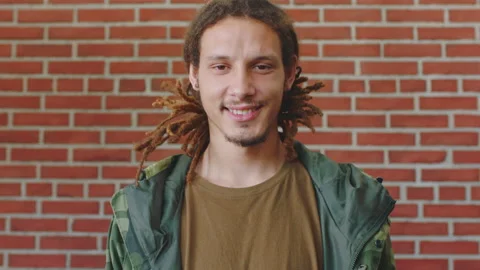 Happy, man and face of student by brick wall with confidence for education Stock Footage 334735625