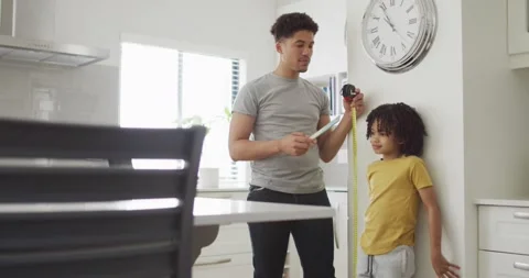 Happy man and his son measure height in kitchen Stock Footage 336056993