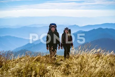 The happy man and a woman with backpacks walking to the mountain Stock Photos