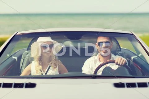 Happy man and woman driving in cabriolet car Stock Photos