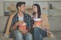 The happy man and a woman eating popcorn and watching movie on the sofa Photo