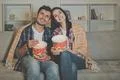 The happy man and a woman eating popcorn and watching movie on the sofa Photo