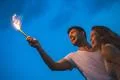The happy man and woman hold a firework stick. evening night time Photo