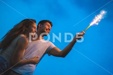 The happy man and woman hold a firework stick. evening night time Stock Photos