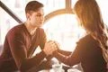 The happy man and a woman holding hands at the restaurant table Photo