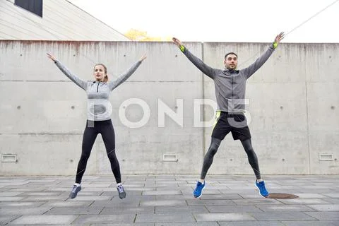 Happy man and woman jumping outdoors Stock Photos