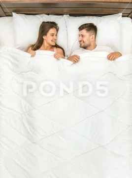 The happy man and woman lay on the bed. View from above Stock Photos