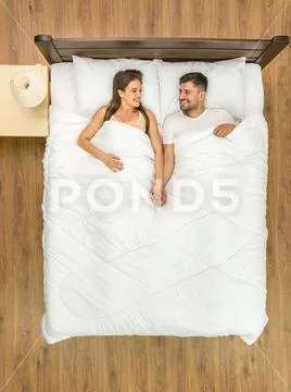 The happy man and woman lay on the bed. View from above Stock Photos