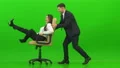 The happy man and a woman playing on the office chair on the green background 4k or 4k+ Resolution