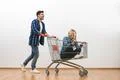 The happy man and a woman ride on the cart on a white wall background Photo