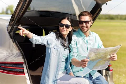 Happy man and woman with road map at hatchback car Stock Photos