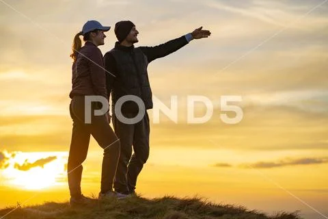 The happy man and a woman standing on the hill on the sunset background Stock Photos