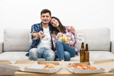 The happy man and a woman watch television on the white wall background Stock Photos