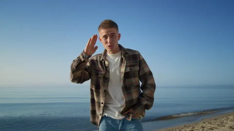 Happy man approaching camera vlogging on beautiful sea shore sunny morning. Video stock 200834029