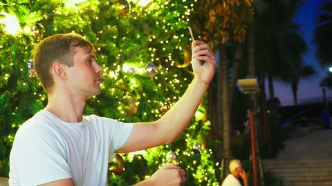 Happy man on the background of the Christmas tree and palm trees in a tropical Stock Footage 102025167