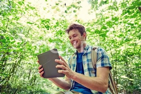 Happy man with backpack and tablet pc in woods Stock Photos