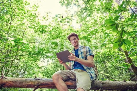 Happy man with backpack and tablet pc in woods Stock Photos