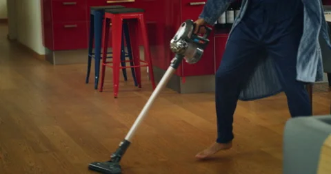 Happy man in bathrobe is dancing while cleaning floor with dust sucker at home. Stock-Footage 141382709