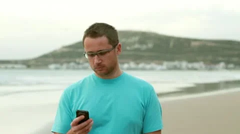 Happy man on the beach talking on mobile phone 스톡 동영상 10758084