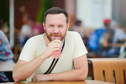Happy man with a beard drinking a soft drink in the city smiling, cold coffee Stock Photos