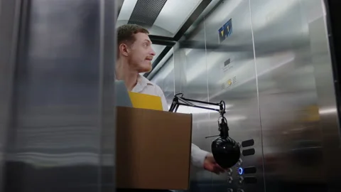 A happy man with a box rides in an elevator on his first working day Stock Footage 219459999