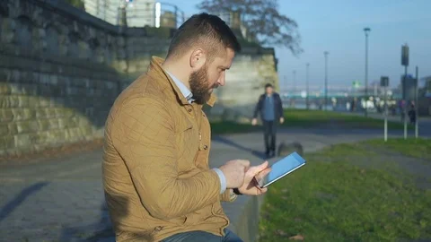 Happy man browsing tablet computer, says someone what time it is now Vídeos de archivo 72775507