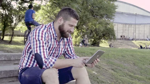 Happy man browsing tablet, sitting on stairs. Vidéo 67247373