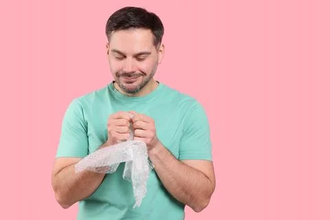 Happy man with bubble wrap on pink background. Space for text Stock Photos