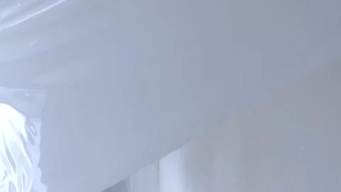 Happy man builder dismanting of stretch suspended ceiling cuts it with knife. Video stock 153084773