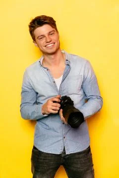 Happy man with camera on yellow background. Stock Photos