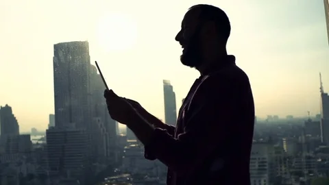 Happy man chatting on tablet computer standing by window at home Stock Footage 71884739