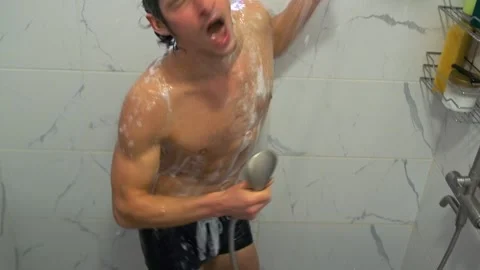Happy man dances in the shower, singing into the showerhead, covered in foam. Video stock 310978005