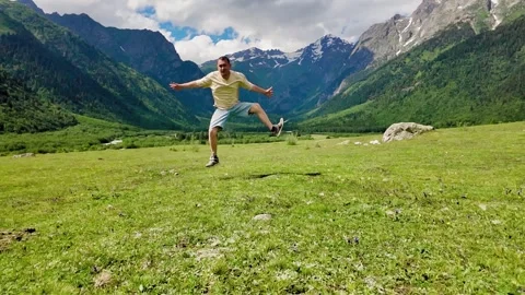 Happy man dancing and jumping in a beautiful mountain valley 스톡 동영상 346320251