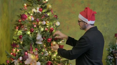 Happy Man Decorating Christmas Tree at Home Stock Footage 294304352