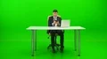 The happy man at the desktop phones on the green background 4k or 4k+ Resolution