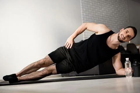 Happy man doing side plank exercise on yoga mat. Healthy lifestyle concept Foto stock