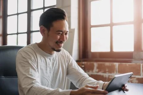 Happy man doing work online from his tablet in his own office. Stock Photos