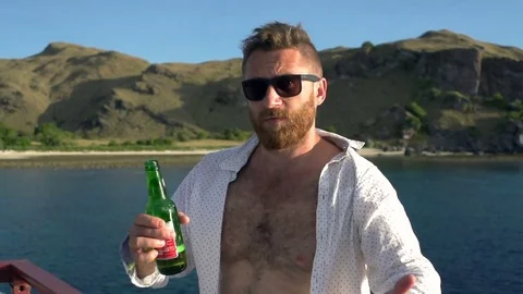 Happy man drinking beer and showing thumbs to the camera, steadycam shot, slow m Video stock 82453454