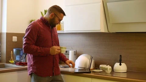 Happy man drinking coffee and dancing in the kitchen while listening music  Stock Footage 73308040