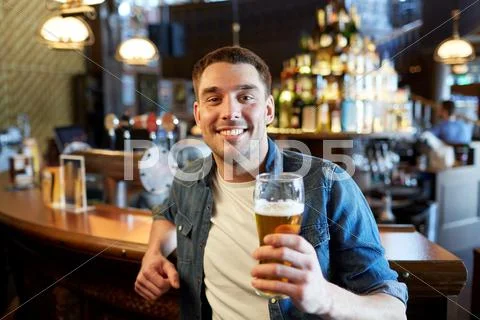 Happy man drinking draft beer at bar or pub Stock Photos